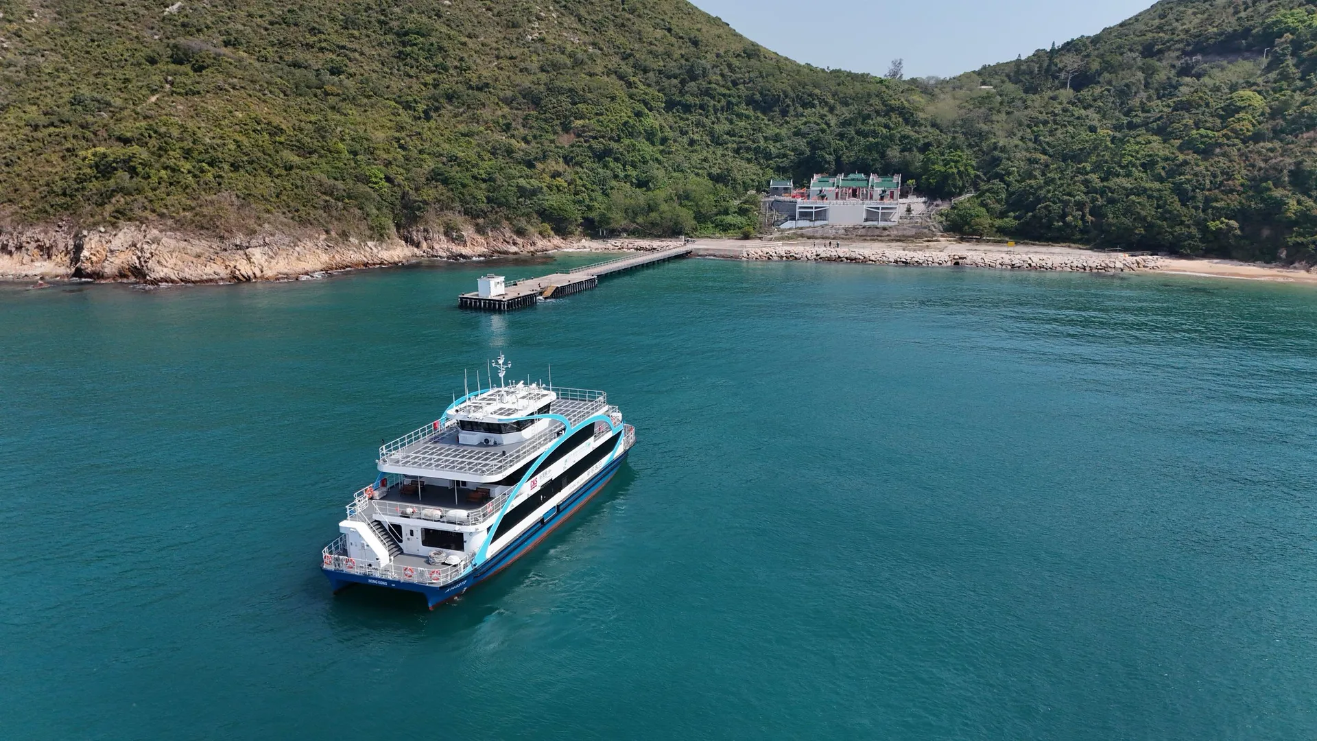 Electric passenger ferry approaching a green coastline